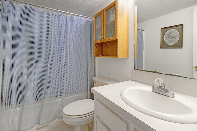 bathroom with toilet, vanity with extensive cabinet space, tile flooring, and a textured ceiling