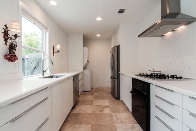 kitchen with white cabinets, wall chimney exhaust hood, sink, and stainless steel appliances