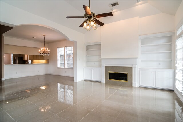 unfurnished living room featuring tile patterned flooring, ceiling fan with notable chandelier, built in features, and a fireplace