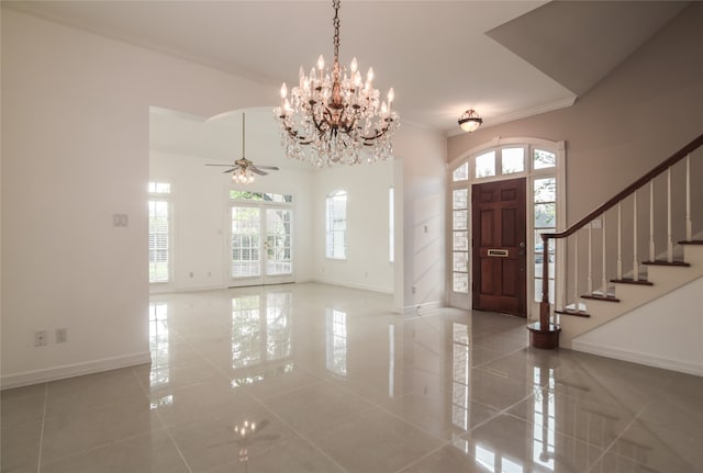 foyer entrance featuring tile patterned flooring, ceiling fan with notable chandelier, a healthy amount of sunlight, and ornamental molding