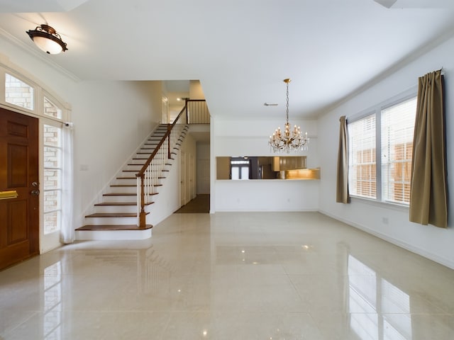 foyer entrance with a chandelier and ornamental molding