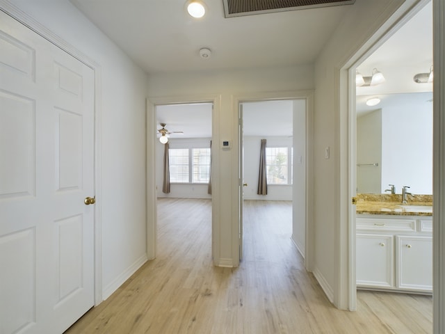 hallway featuring light wood-type flooring and sink