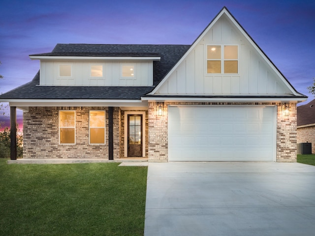 view of front of home featuring a lawn, central AC, and a garage