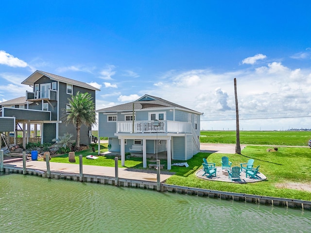 rear view of house with a balcony, a water view, a patio, and an outdoor fire pit