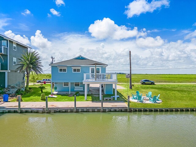 back of property featuring a water view, a balcony, and a yard