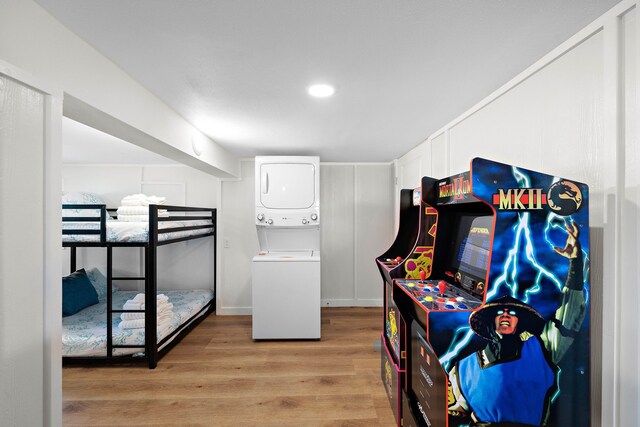 bedroom with stacked washing maching and dryer and light hardwood / wood-style floors