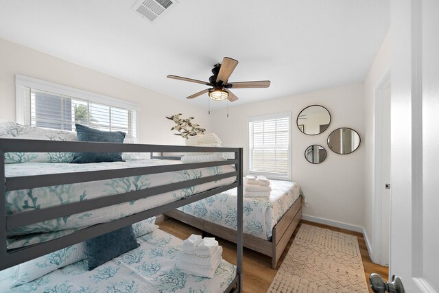 bedroom with multiple windows, light hardwood / wood-style floors, and ceiling fan