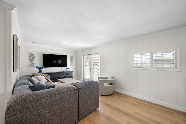 living room featuring crown molding, a healthy amount of sunlight, and light wood-type flooring