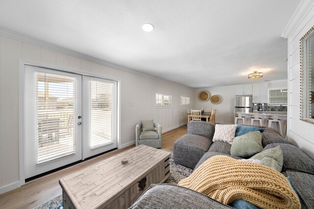 living room with light hardwood / wood-style flooring, ornamental molding, and a healthy amount of sunlight