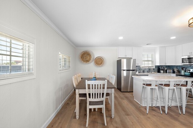 dining room featuring crown molding, sink, and light hardwood / wood-style flooring