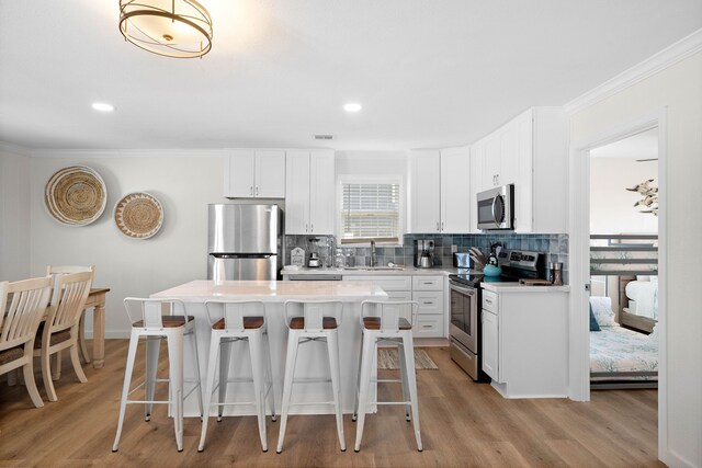 kitchen with stainless steel appliances, sink, a kitchen island, and white cabinets