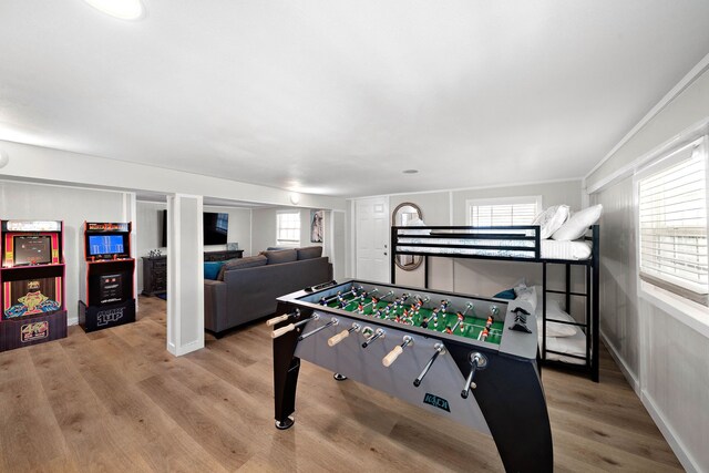 recreation room with wood-type flooring and crown molding