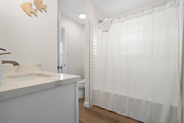 full bathroom with shower / bath combo with shower curtain, wood-type flooring, toilet, and vanity