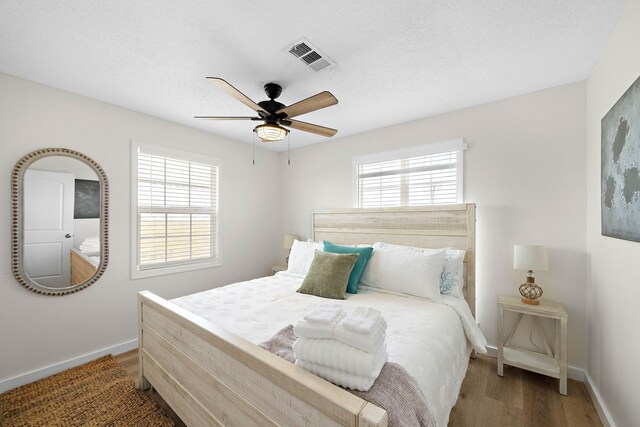 bedroom with hardwood / wood-style flooring, a textured ceiling, and ceiling fan