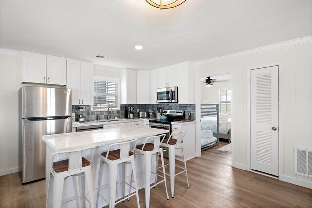 kitchen with white cabinetry, appliances with stainless steel finishes, a kitchen island, and a breakfast bar area