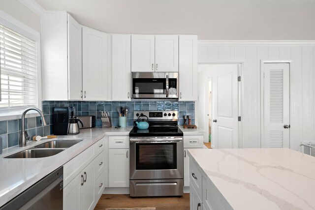 kitchen with white cabinetry, appliances with stainless steel finishes, sink, and light stone counters