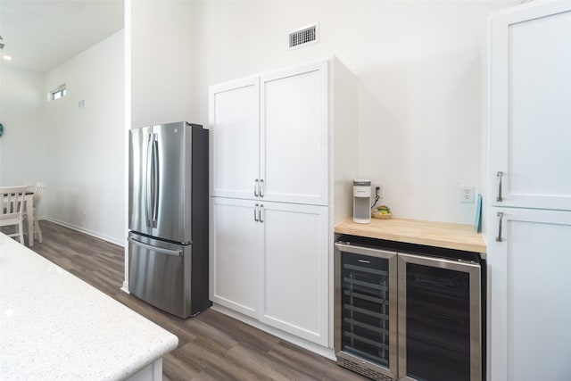 kitchen with dark wood-type flooring, beverage cooler, stainless steel refrigerator, and white cabinets