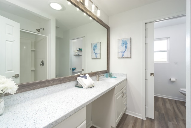 bathroom with wood-type flooring, toilet, walk in shower, and vanity