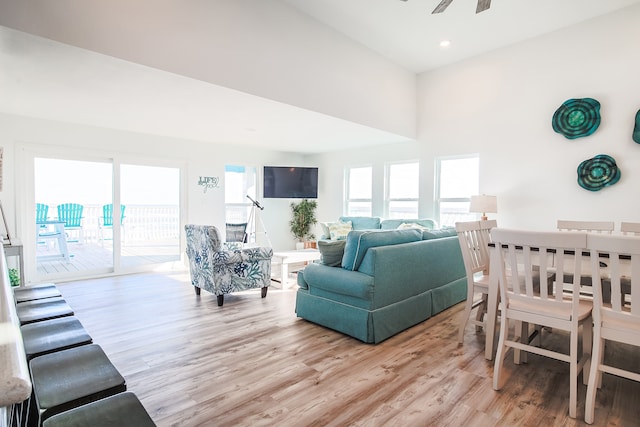 living room featuring light wood-type flooring, plenty of natural light, a high ceiling, and ceiling fan