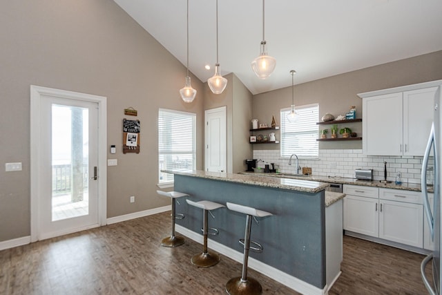 kitchen featuring backsplash, light stone counters, decorative light fixtures, white cabinets, and a center island