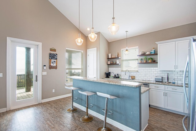 kitchen featuring stainless steel fridge, tasteful backsplash, decorative light fixtures, light stone counters, and white cabinetry