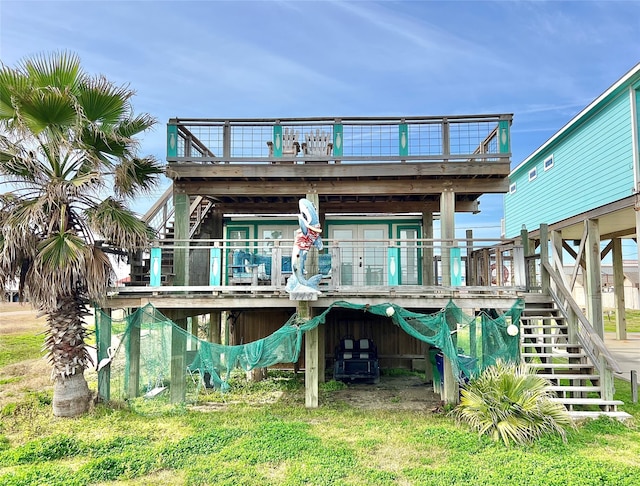 back of house featuring a balcony, a deck, and a lawn