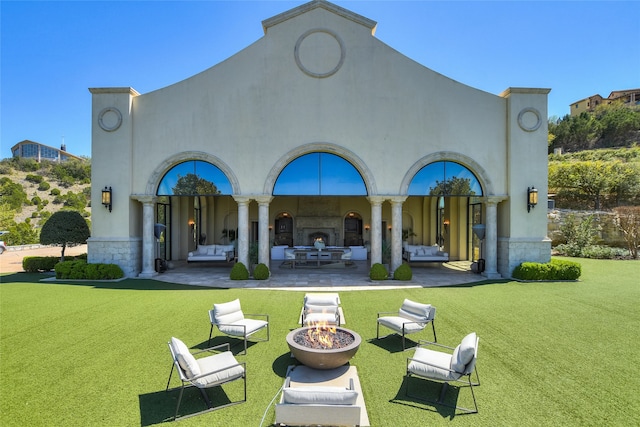 back of property featuring a lawn, a patio area, and an outdoor living space with a fire pit