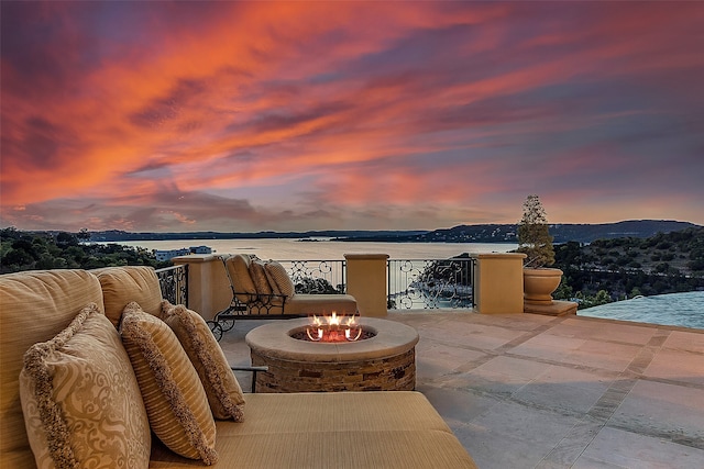 patio terrace at dusk with a fire pit and a water view