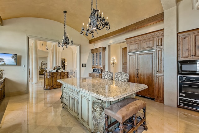 kitchen featuring a center island, a notable chandelier, light stone countertops, a breakfast bar, and black appliances