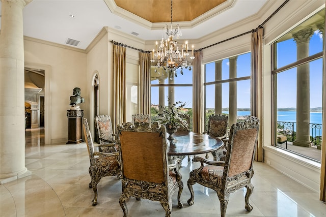 dining space with plenty of natural light, light tile flooring, a water view, decorative columns, and an inviting chandelier