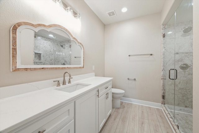 bathroom with vanity, hardwood / wood-style flooring, toilet, and a shower with door