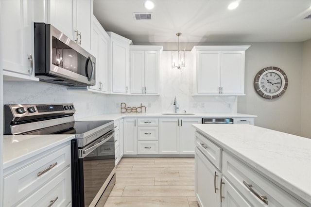 kitchen featuring sink, light hardwood / wood-style flooring, decorative light fixtures, white cabinetry, and stainless steel appliances