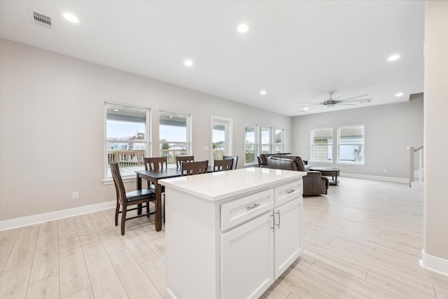 kitchen with white cabinets, a center island, light hardwood / wood-style floors, and ceiling fan