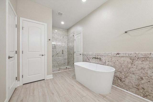 bathroom featuring wood-type flooring, tile walls, and plus walk in shower