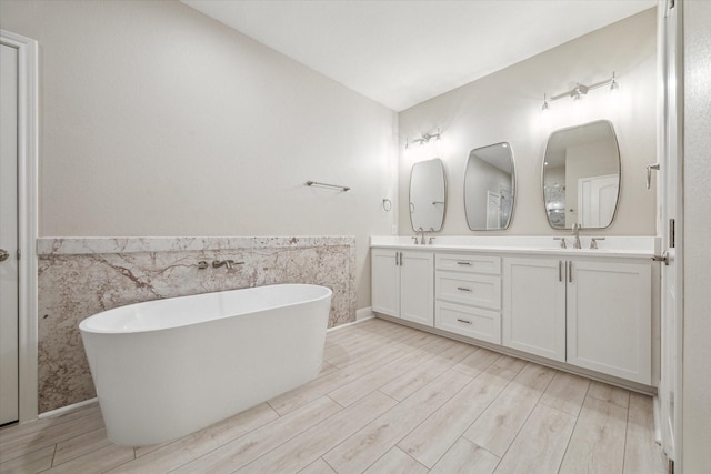 bathroom with hardwood / wood-style floors, vanity, a bath, and tile walls