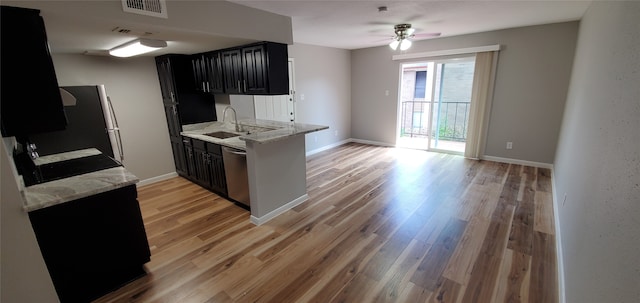 kitchen with light stone countertops, sink, ceiling fan, light hardwood / wood-style floors, and appliances with stainless steel finishes