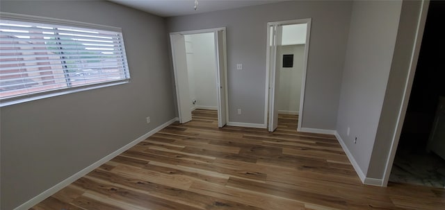 unfurnished bedroom with a walk in closet, a closet, baseboards, and wood finished floors