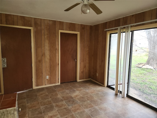 tiled spare room featuring wood walls and ceiling fan