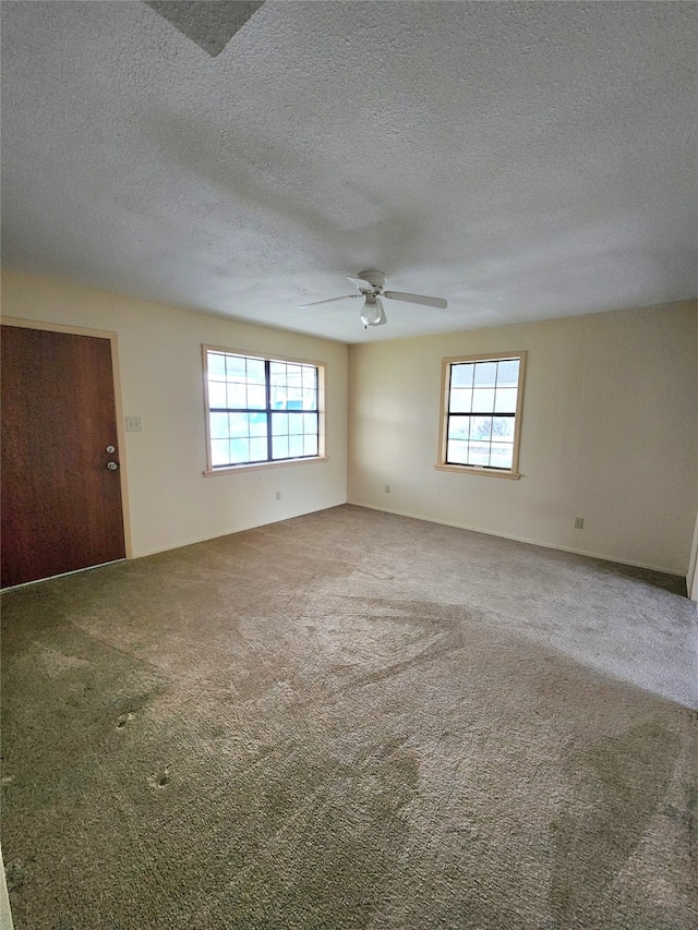 unfurnished room featuring carpet floors, ceiling fan, a textured ceiling, and a wealth of natural light