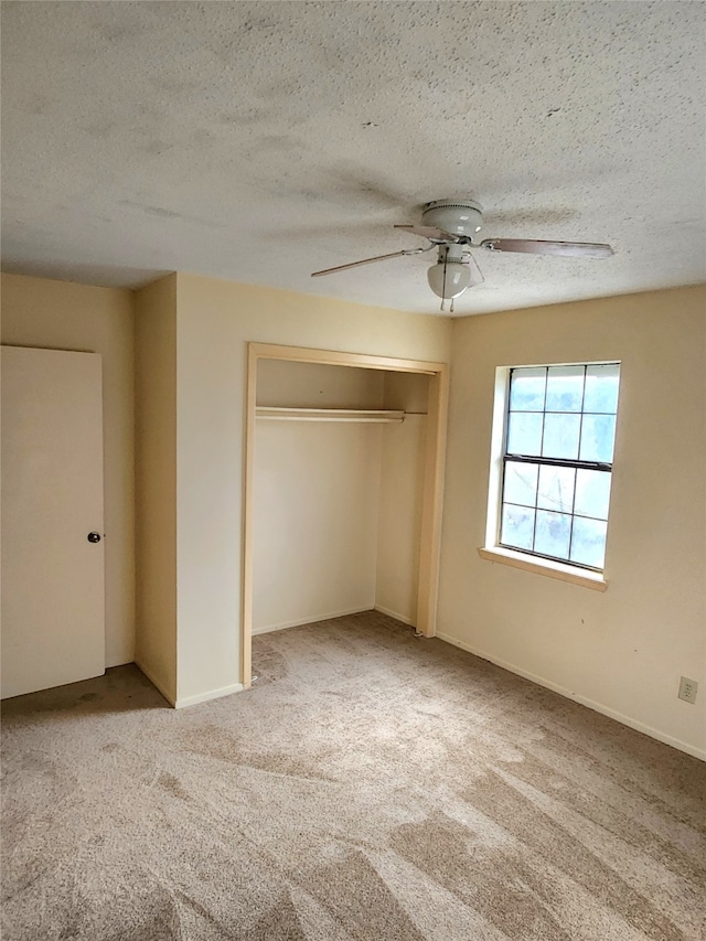 unfurnished bedroom featuring light carpet, a textured ceiling, a closet, and ceiling fan