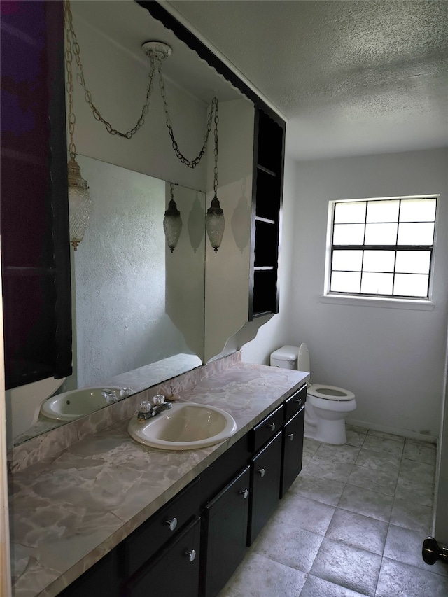 bathroom with toilet, a textured ceiling, tile floors, and vanity with extensive cabinet space