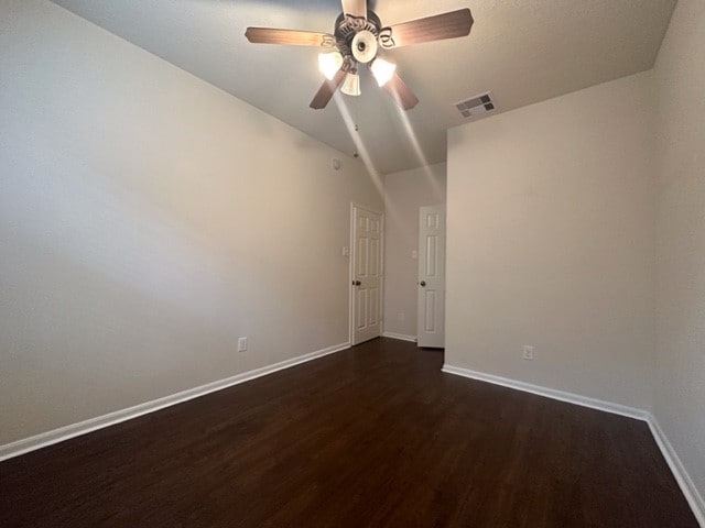 spare room with ceiling fan, dark wood-type flooring, and vaulted ceiling