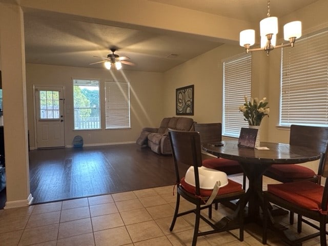 tiled dining space with ceiling fan with notable chandelier