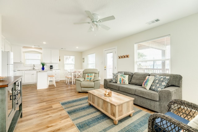 living room with sink, ceiling fan, and light hardwood / wood-style flooring