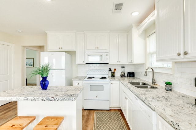 kitchen with white appliances, white cabinetry, and light stone counters