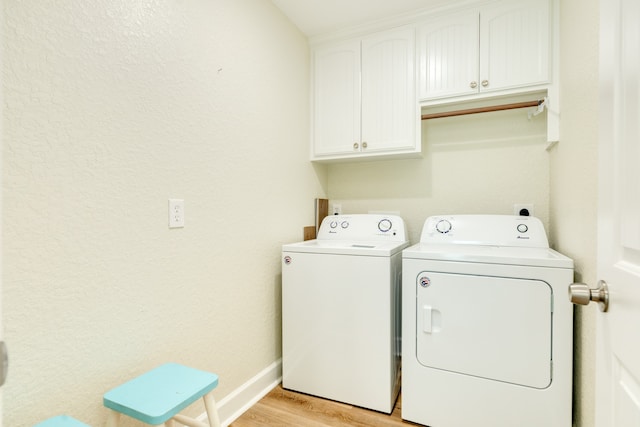 laundry area featuring cabinets, washing machine and clothes dryer, and light wood-type flooring