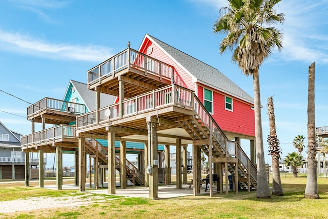 rear view of property with a lawn, a balcony, and a deck