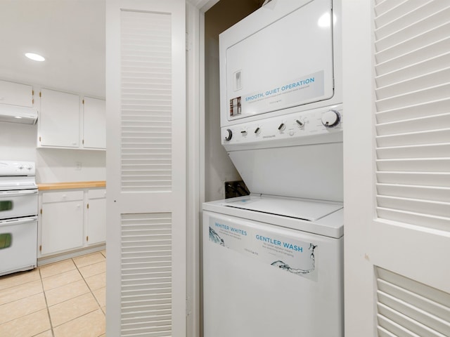 laundry area featuring stacked washer and clothes dryer and light tile flooring