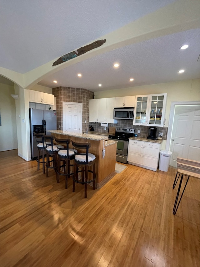 kitchen featuring appliances with stainless steel finishes, light wood-type flooring, a kitchen island, and white cabinets