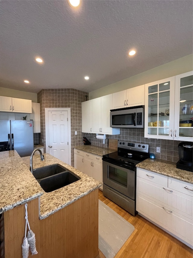 kitchen featuring stainless steel appliances, an island with sink, sink, and white cabinetry